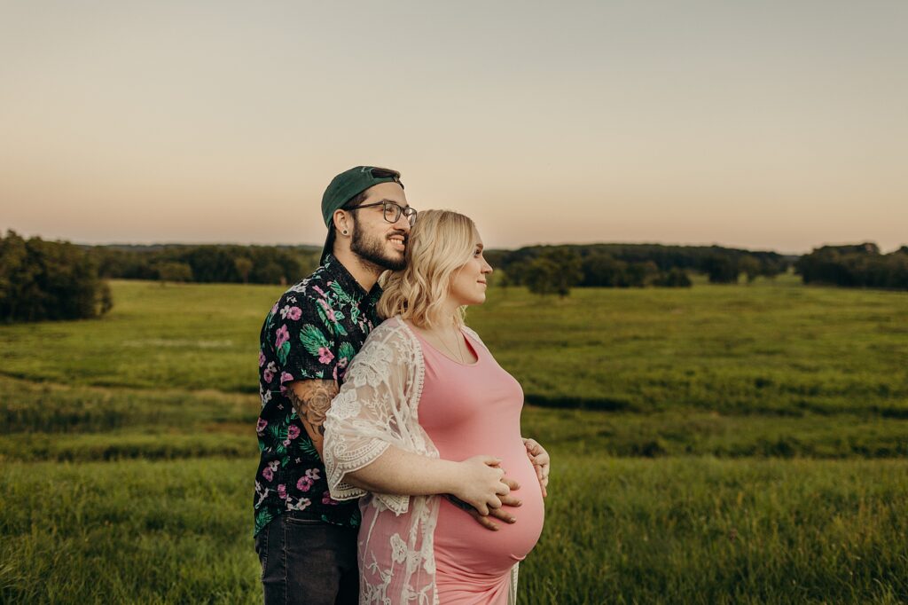 a couple standing in front of a summer sunset for their maternity photos in valley forge 