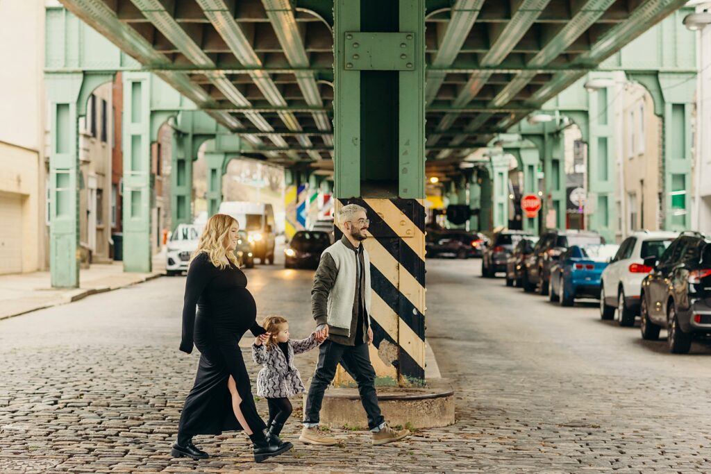 a family of 3 walking through manayunk during their lifestyle family and maternity photoshoot 