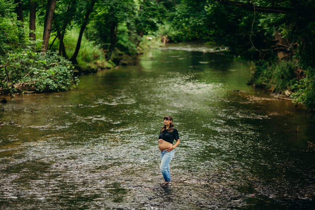 a pregnant woman standing in the Valley Forge river during her maternity photoshoot. 