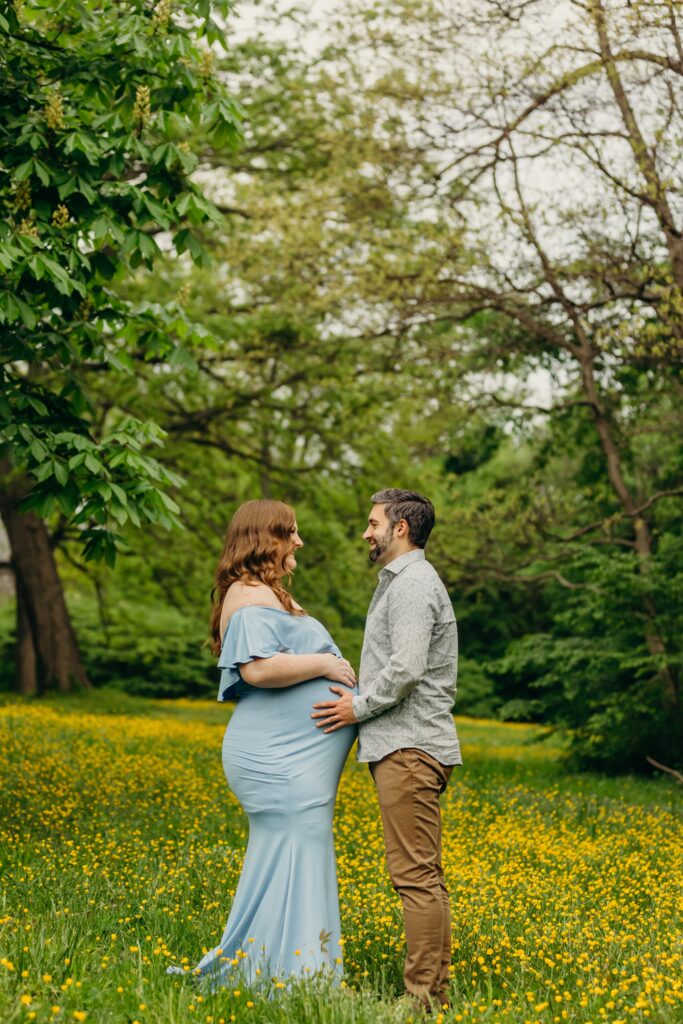 a couple standing in a yellow buttercup flower field at Awbury Arboretum for their maternity session.