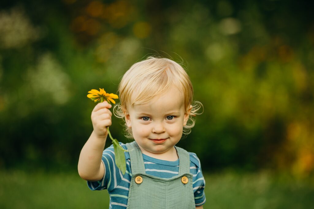 a baby boy holding up a flower in Mt. Airy in the Summer