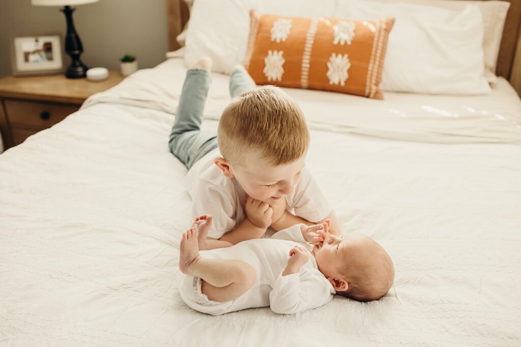 older brother laying with his newborn baby brother in his Philadelphia home during a lifestyle newborn session 