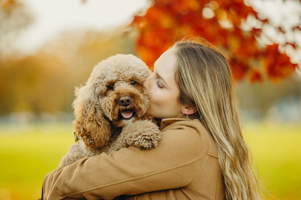 Woman kissing her golden doodle during their fall pet photo session in Philadelphia