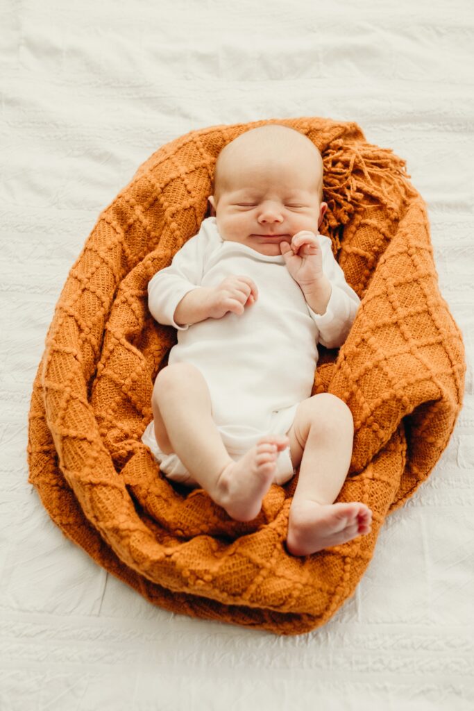 newborn baby lying on an orange blanket during a lifestyle newborn shoot in Philadelphia, Pennsylvania 