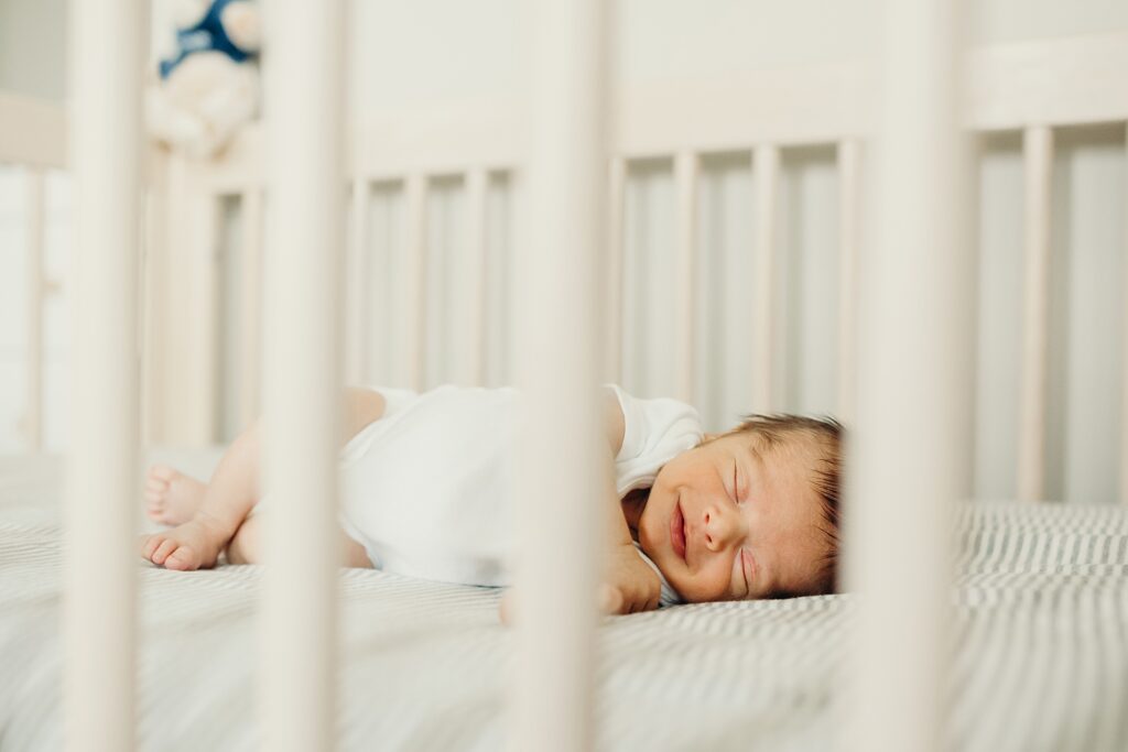 newborn baby boy smiling while sleeping during his lifestyle Philadelphia newborn photo session