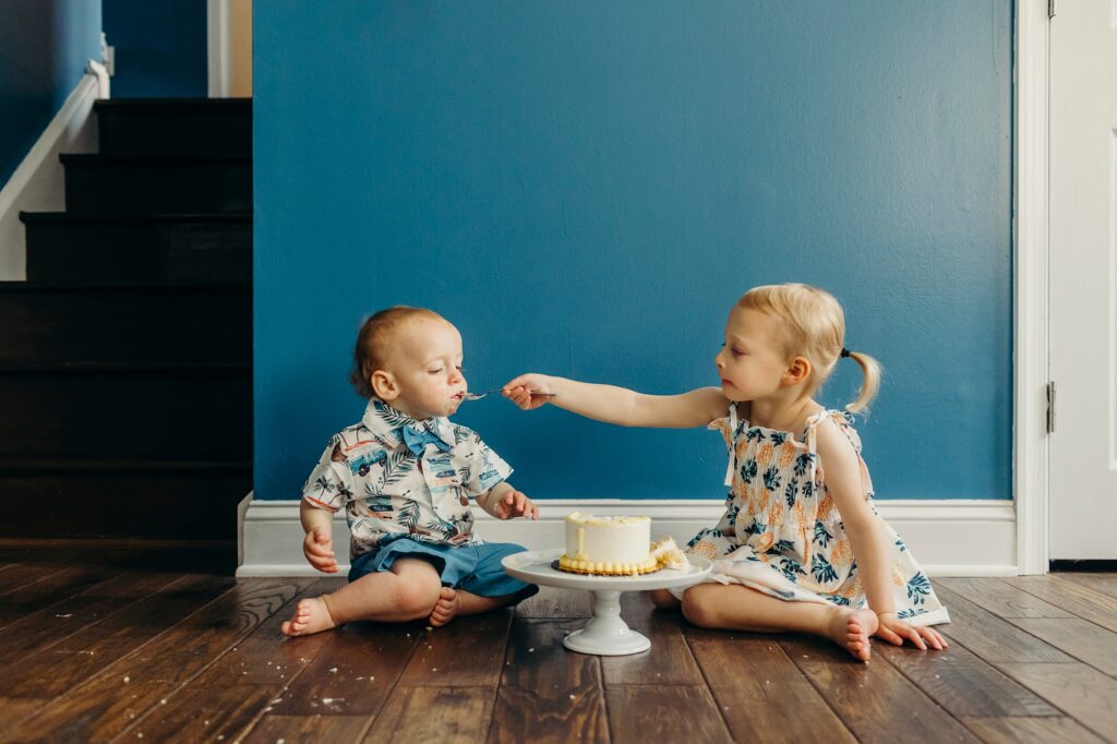 a big sister feeding her baby brother his birthday cake during Philadelphia cake smash photoshoot