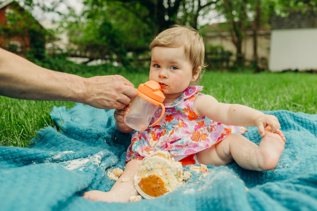 baby girl drinking from her sippy cup during at home lifestyle photoshoot