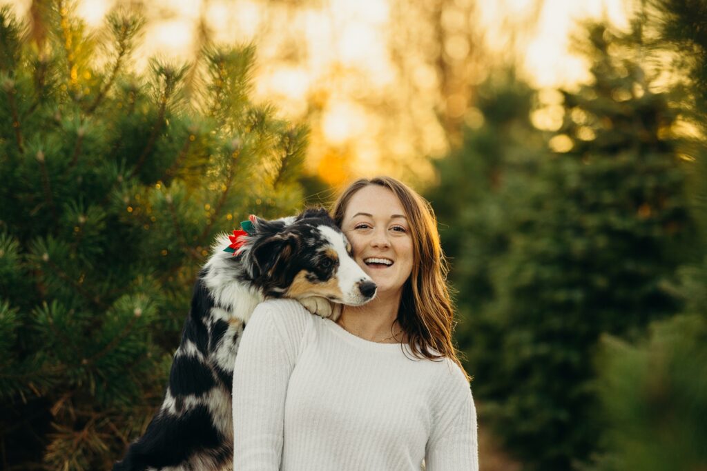 a dog resting her head on her owners shoulders during a Philadelphia pet photo session at a Christmas Tree farm