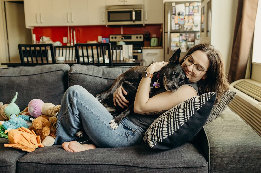 a woman cuddling on her couch with her dog during a lifestyle pet session in Philadelphia.