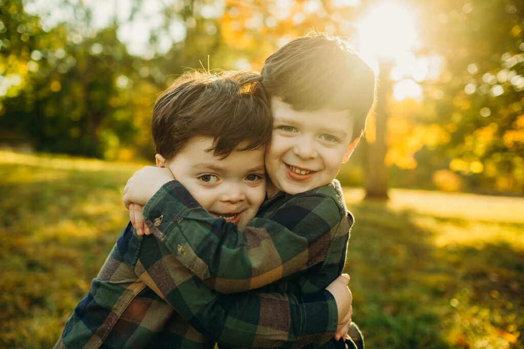 Twin toddler boys hugging each other during a fall family session in Valley Forge Park. 