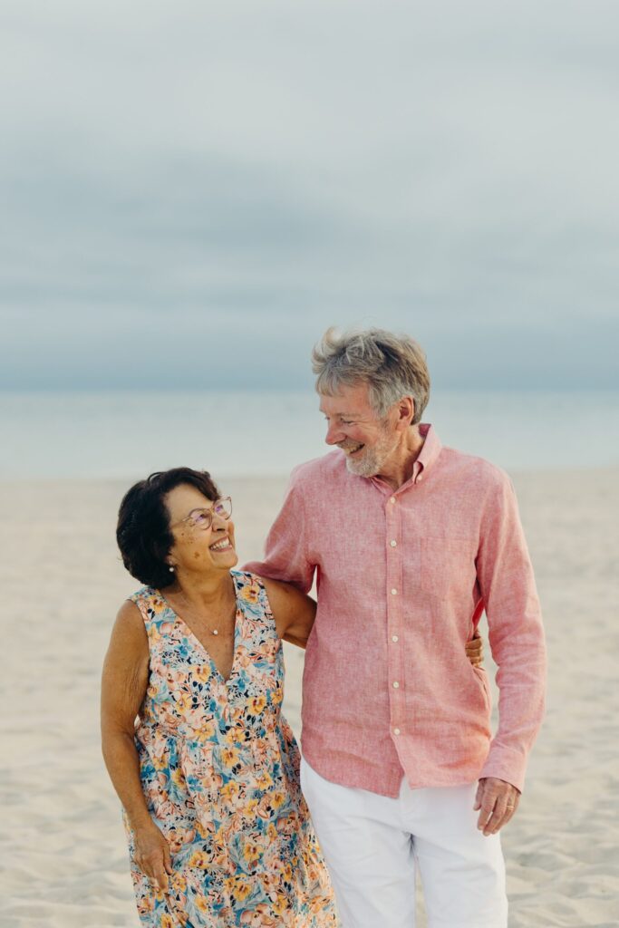 a loving older couple walking along the Ocean City, NJ shoreline  during an extended family beach photo session