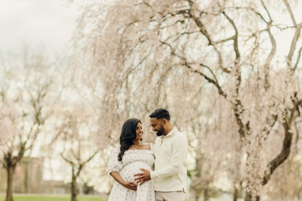 A young Philly couples lifestyle maternity photoshoot during the Spring's Cherry blossom flower season in Fairmount Park at the Horticulture Center. 