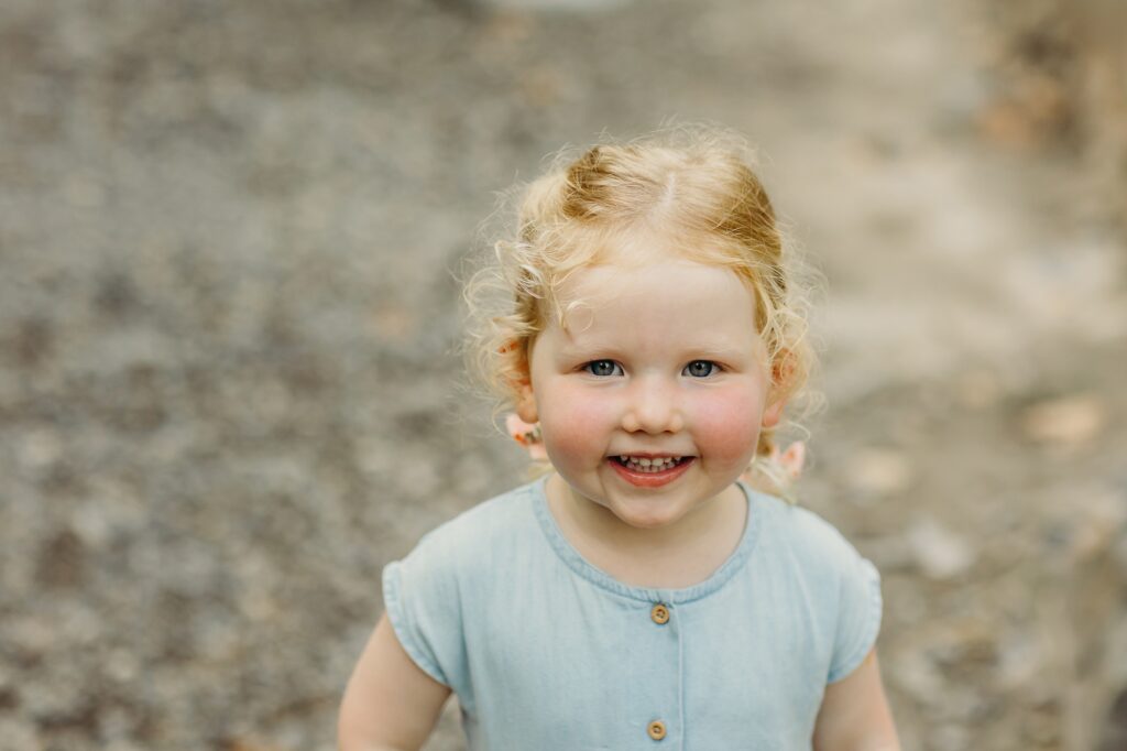 a toddler smiling during a lifestyle summer family photoshoot in Wisshahickon Park. 
