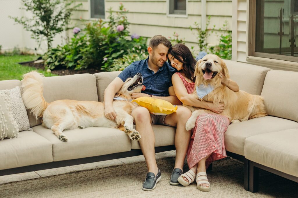 a young Pennsylvania couple with their two golden retrievers in their Yardley backyard during a lifestyle pet photoshoot. 