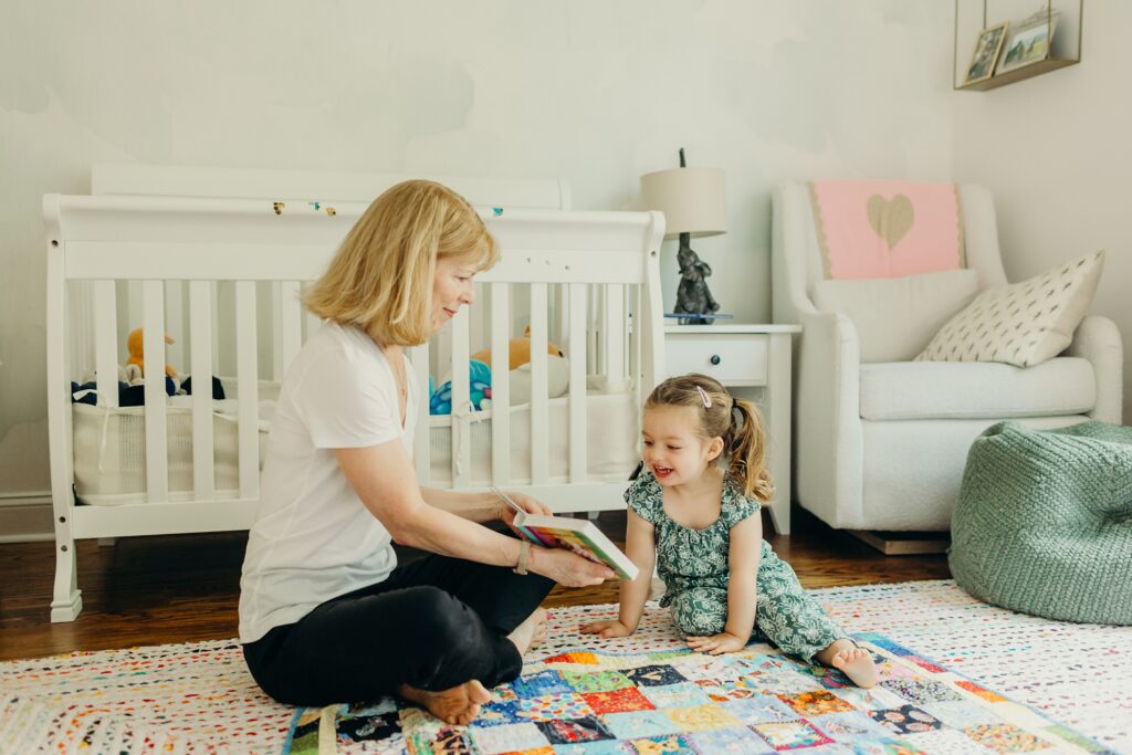 a young girl spending time and reading with her grandmother during a lifestyle at home family photoshoot in Center City Philly. 