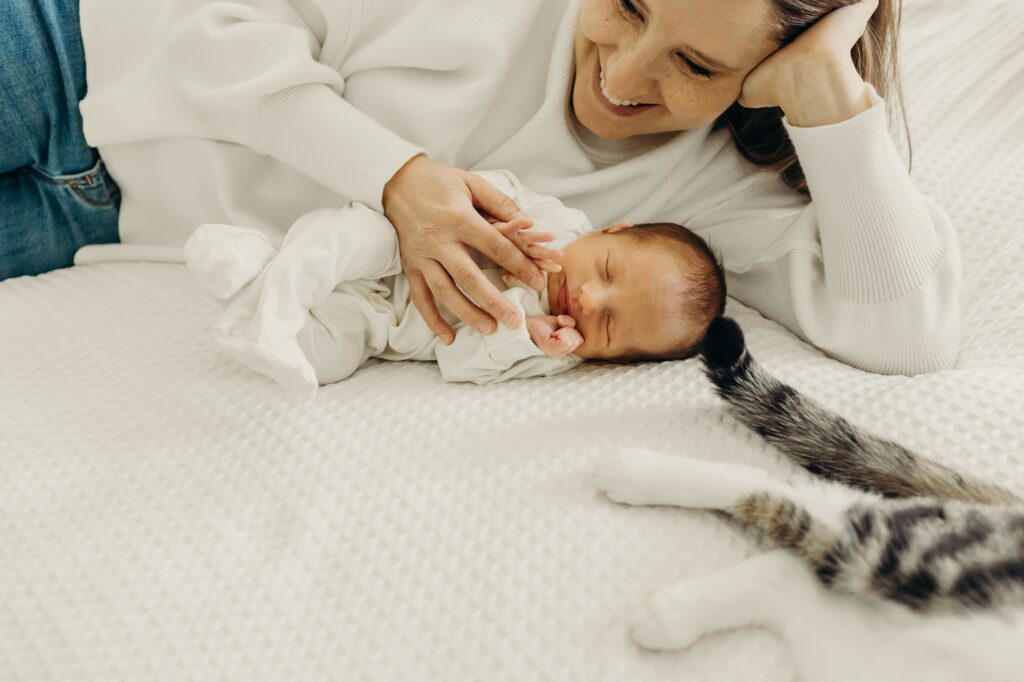 Newborn baby boy sleeping next to his mother and cat during a lifestyle newborn photo session in South Philly. 