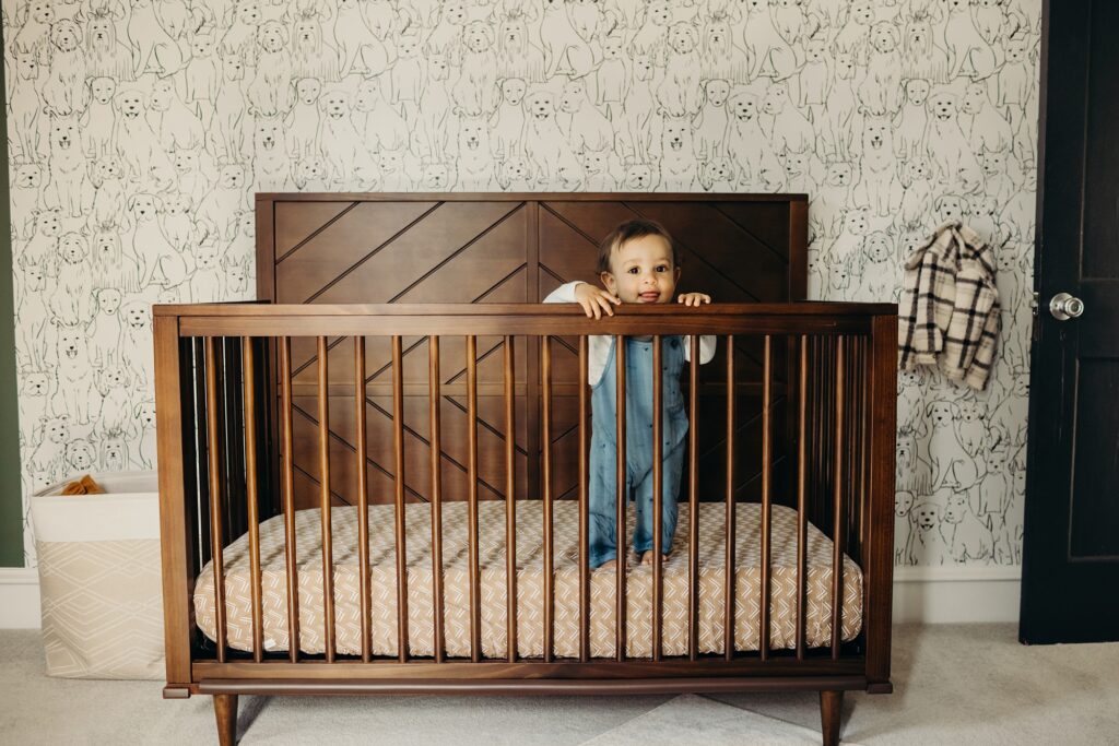 one-year-old baby boy standing in his minimalistic nursery in his Pennsylvania home during a lifestyle family photo session 