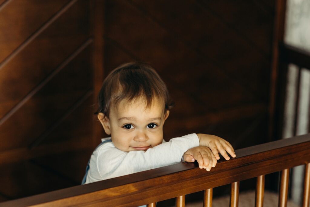 a baby standing up in his crib during his lifestyle at home family photoshoot in Conshohocken, Pennsylvania 